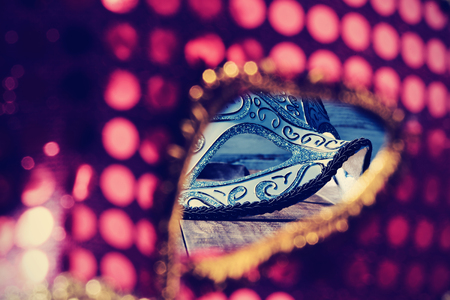 an elegant blue and black carnival mask seen through the eye hole of a red maskの写真素材