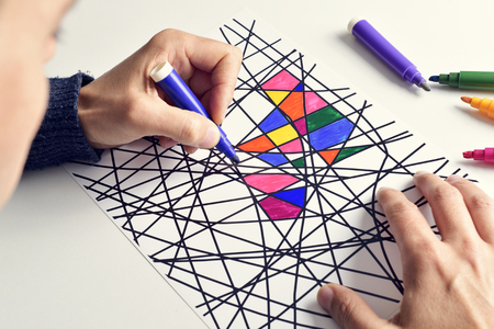 closeup of a young man coloring an abstract drawing.の写真素材