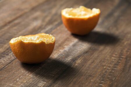 closeup of an orange cut in half on a dark wooden tableの写真素材