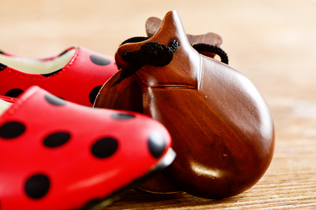 closeup of a pair of castanets and a pair of typical dot-patterned red flamenco shoes, on a wooden surfaceの写真素材