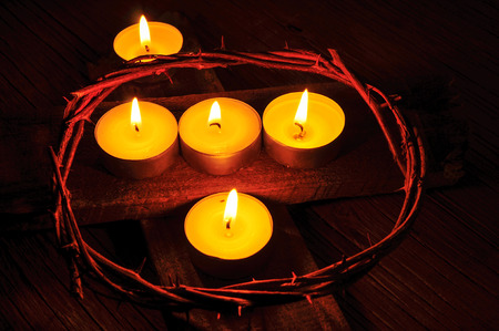 closeup of a recreation of the crown of thorns of Jesus Christ and some lit candles on a wooden crossの写真素材