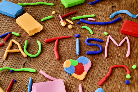 the word autism made from modelling clay of different colors on a rustic wooden surfaceの写真素材
