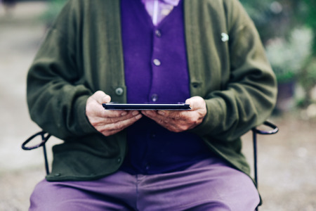 closeup of an old caucasian man using a tablet computer outdoorsの写真素材