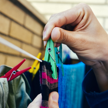 closeup of a young caucasian man hanging up some clothes with clothespins in a clothes lineの写真素材