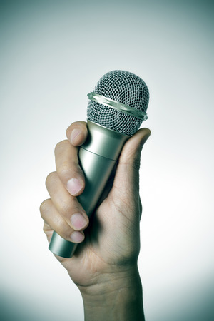 closeup of a young caucasian man with a microphone in his hand, with a vignette addedの写真素材