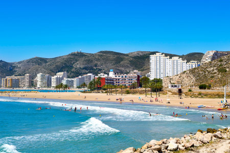 Cullera, Spain - June 23, 2016: Sunbathers at Raco Beach in Cullera, Spain, with the the San Antonio...