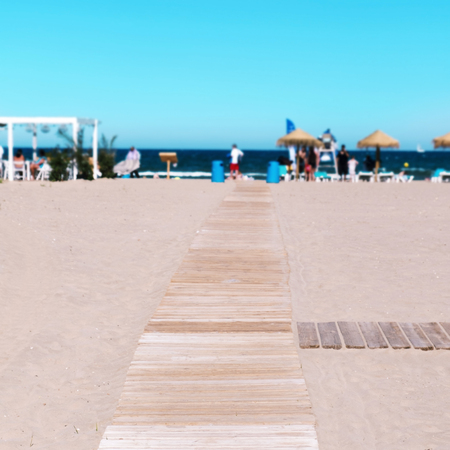 wooden boardwalk at La Malvarrosa Beach in Valencia, Spain, with the Mediterranean sea and unrecognizable sunbathers in the backgroundの写真素材