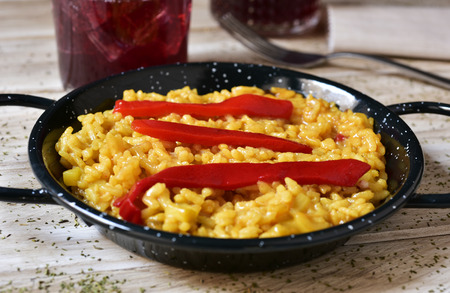 closeup of a spanish paella served as tapas in a small paella pan, on a rustic wooden tableの写真素材
