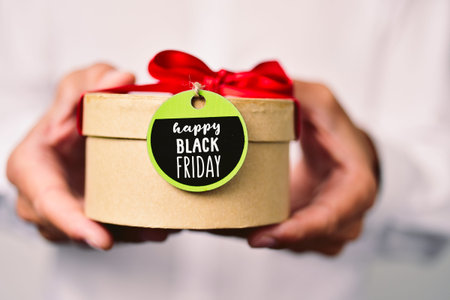 closeup of a young caucasian man in a white shirt holding a gift box with a label tied to it and the...