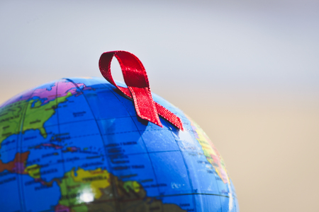 closeup a world globe with a red ribbon for the fight against AIDSの写真素材
