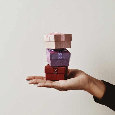 closeup of a young caucasian woman holding a balanced stack of small gifts in the palm of her handの写真素材