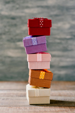 a stack of some cozy gifts wrapped in different papers and tied with ribbons of different colors on...