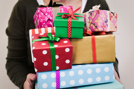 closeup of a young caucasian woman holding a pile of gifts in her hands wrapped in nice papers and...