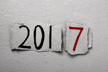 the number 2017, as the new year, handwritten in some pieces of rustic paper in black and red, placed on a background of the same rustic paperの写真素材