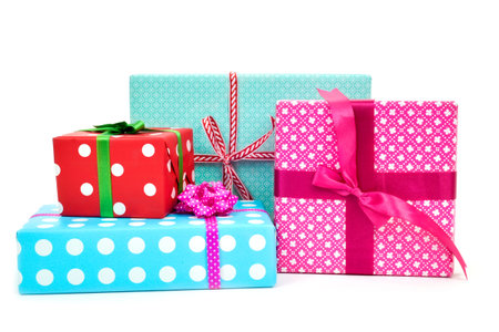 closeup of a pile of gifts wrapped in nice papers and tied with ribbons of different colors on a...