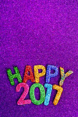 closeup of some glittering letters of different colors forming the text happy 2017, on a violet...