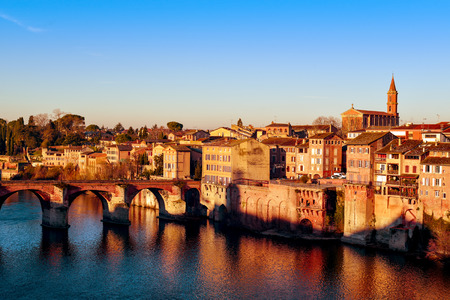 a view of the Tarn River as it passes through Albi, in France, with the Pont Vieux bridge to the left and the Church of Notre Dame du Breuil highlighting to the rightの写真素材