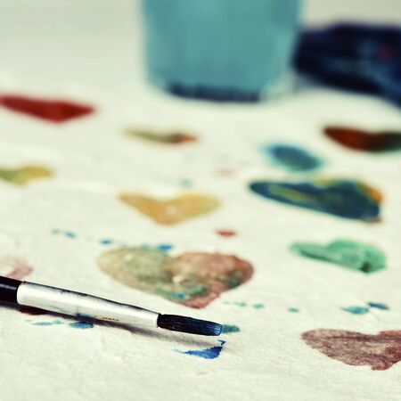 closeup of a piece of paper with some hearts of different colors painted with watercolor paintの写真素材