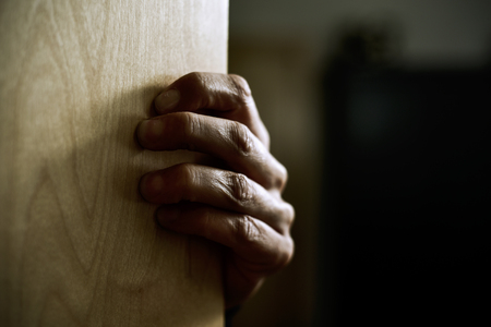 closeup of the hand of a young caucasian man popping out strongly from behind a doorの写真素材