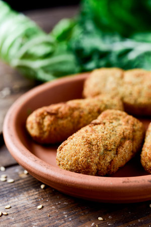 closeup of an earthenware plate with some homemade croquetas, spanish croquettes, on a rustic wooden...