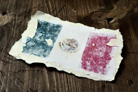 the flag of Mexico in an aged piece of paper on a rustic wooden backgroundの写真素材