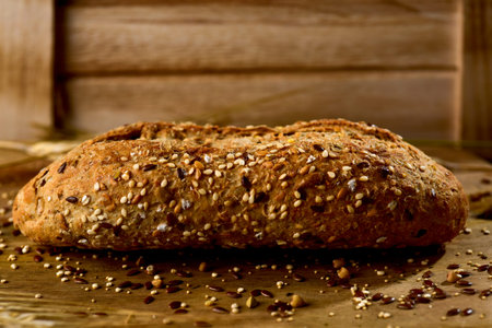 closeup of a wholemeal bread roll topped with different seeds, such as sesame and poppy seeds, on a...