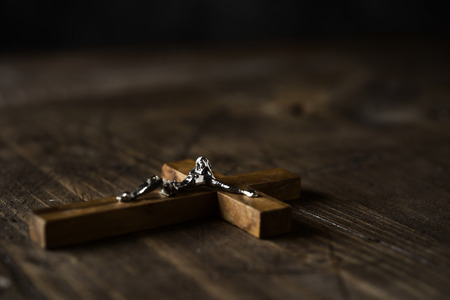 closeup of an old christian crucifix on a rustic wooden surfaceの写真素材