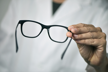 closeup of a young optician man bringing a pair of eyeglasses to the observerの写真素材