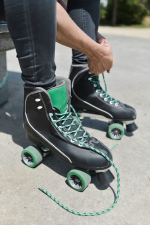 closeup of a young caucasian man tying the laces of his quad skates in an outdoors skate park