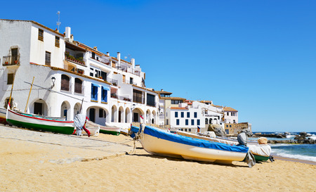 some old fishing boats stranded on the Barques Beach in Calella de Palafrugell, Costa Brava, Catalonia, Spain, with its characteristics white houses with portico in the backgroundの写真素材