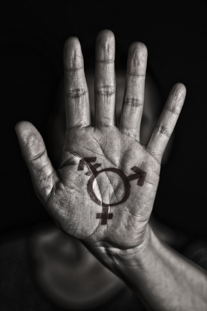 closeup of a transgender symbol painted in the palm of the hand of a young caucasian person in black and whiteの写真素材