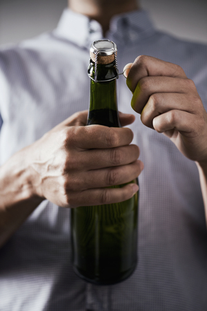 closeup of a young caucasian opening a bottle of champagneの写真素材