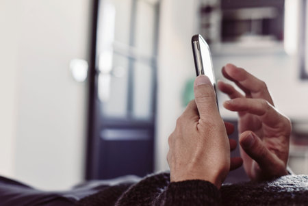 closeup of a young caucasian man using his smartphone lying down on a couch or a bed
