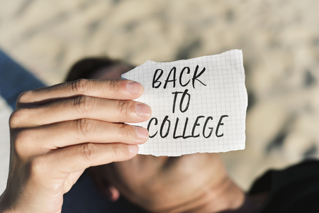 closeup of a caucasian student outdoors with a note with the text back to college written in itの写真素材