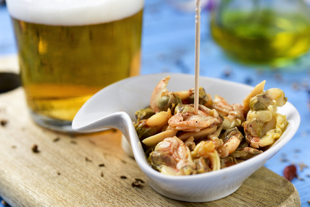 closeup of a ceramic bowl with seasoned clams served as appetizer, next to a glass of beerの写真素材