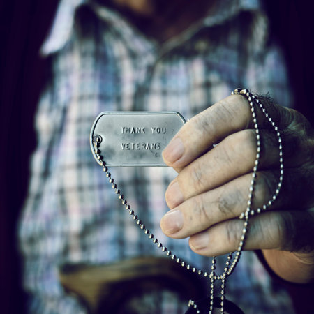 closeup of an old caucasian man showing a dog tag with the text thank you veterans engraved in itの写真素材