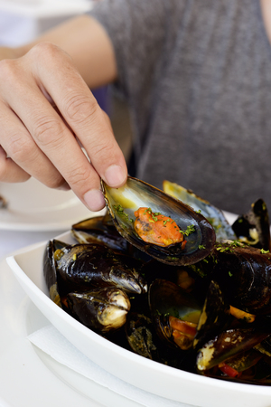 closeup of a young man eatign some mejillones a la marinera, spanish mussels in marinara sauceの写真素材