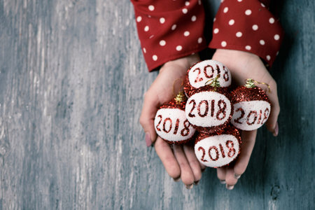 a young caucasian woman wearing a red dress patterned with white dots holding some christmas balls...