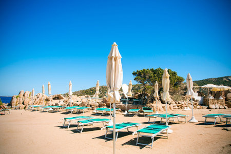 some sunloungers and umbrellas in a beach in Baja Sardinia, Sardinia, Italyのeditorial素材