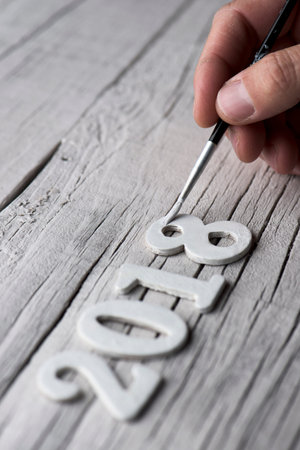 closeup of a young caucasian man painting white the four numbers of the number 2018, as the new...