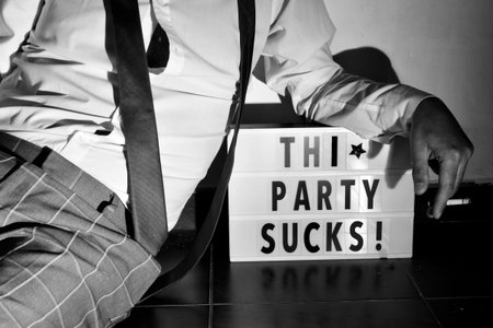 closeup of a young man lying on the floor wearing a loose black tie and smoking a cigarette, and the...