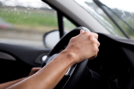 closeup of a young caucasian man driving a car in a rainy day