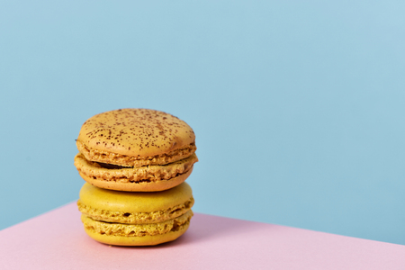 a pile of delicious macarons of different flavors on a pink and blue background with a blank space on the rightの写真素材