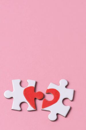 two separated pieces of a puzzle which together form on a pink background with a blank space on top, depicting the idea of rupture or cooperationの写真素材