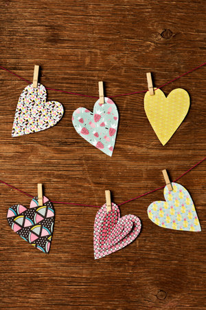 some nice hearts cut out from papers with different patterns hung with clothespins in some clothes...