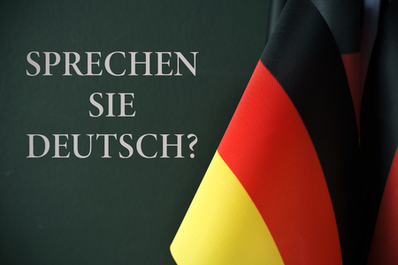 some flags of germany and the question sprechen sie deutsch?, do you speak german? written in german, against a dark green backgroundの写真素材