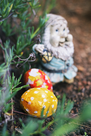 closeup of some homemade decorated easter eggs, made by myself, hidden in the garden next to an old and weathered garden gnomeの写真素材
