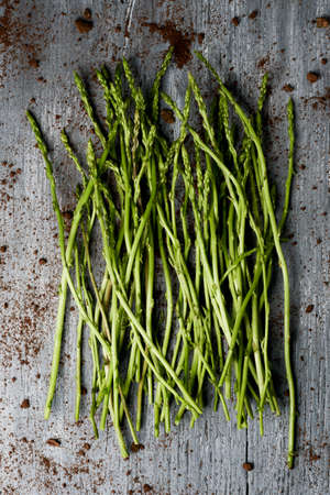 closeup of a bunch of wild asparagus on a gray rustic wooden tableの写真素材