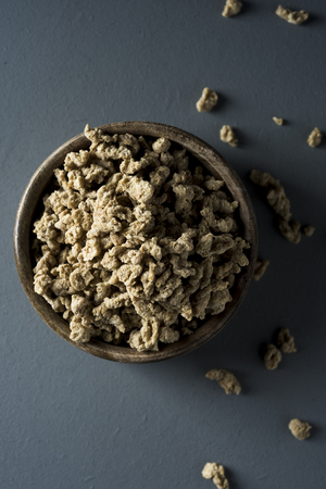 high angle view of some chunks of textured soy protein in a rustic boxwood bowl, placed on a gray wooden tableの写真素材