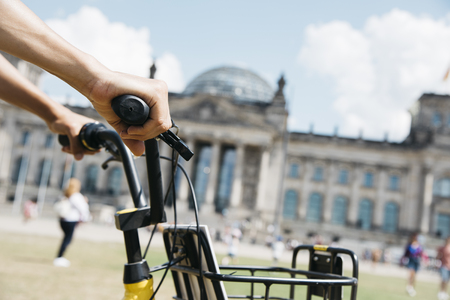 closeup of a young caucasian man riding a bike by the Platz der Republik square, in Berlin, Germany, with the Reichstag building in the backgroundの写真素材